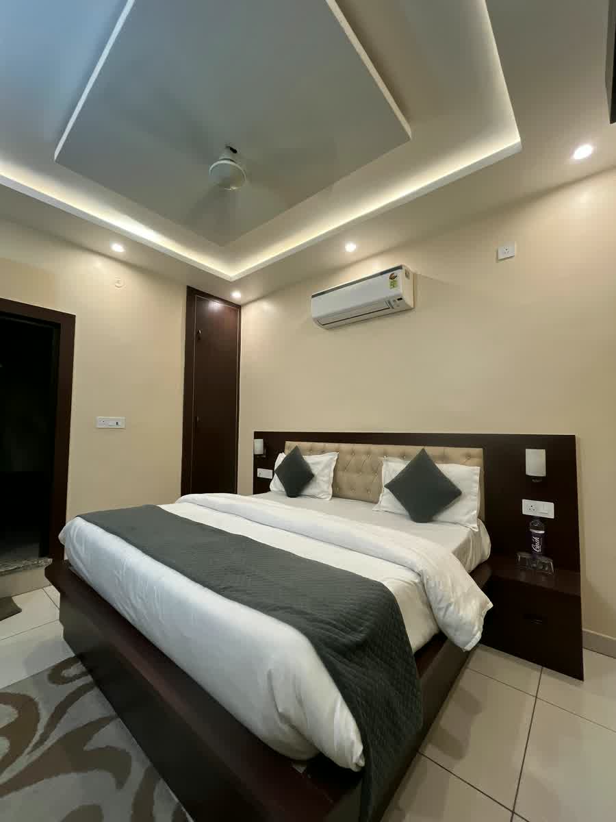 A guest room with a light tiled floor, a patterned rug and a grey runner on the bed.