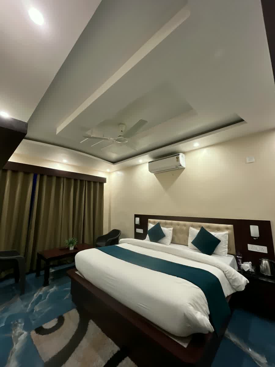 A guest room with a teal runner across the bed, a blue marble floor and a lit cove in the ceiling.