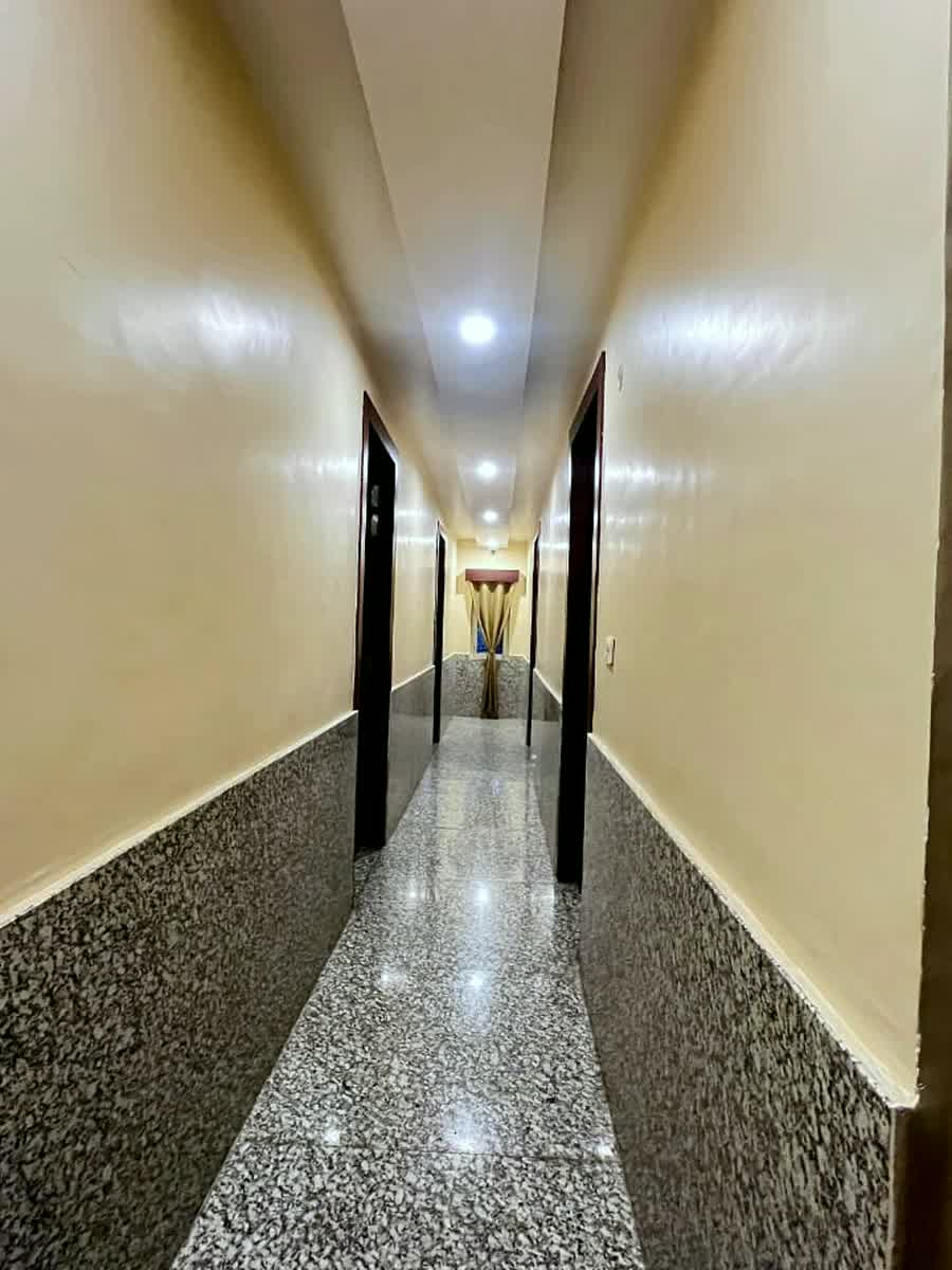 A long guest-floor corridor with a speckled stone dado and a lit end.