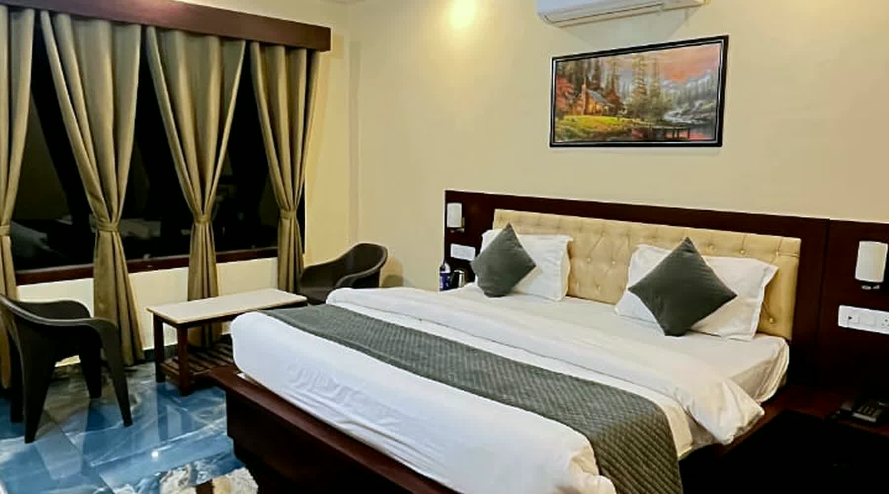 A guest room seen wide: bed, framed picture, armchair by the window.